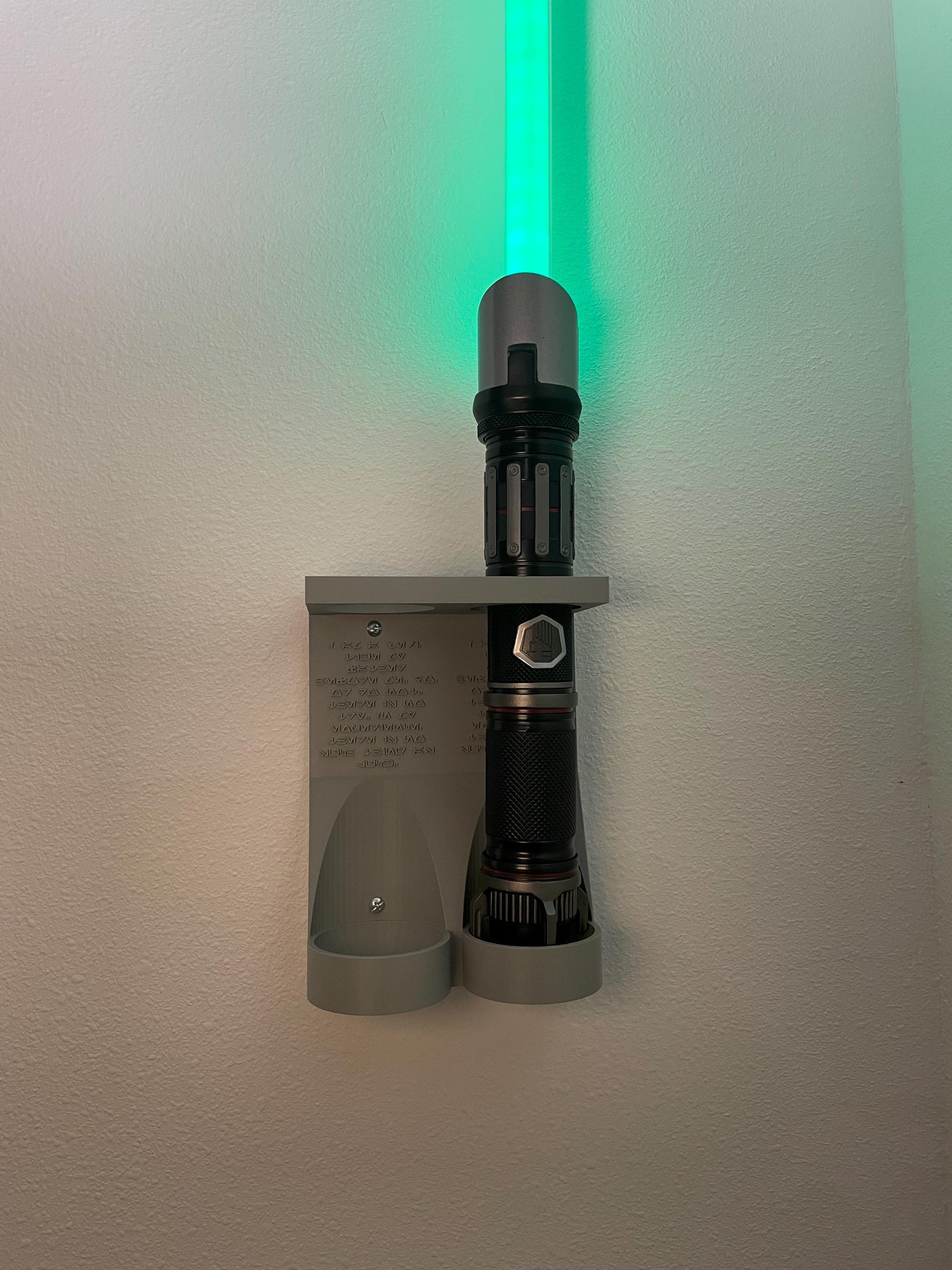 Savis Workshop Dual Lightsaber Mount by RobertsDesignandTech as shown in our Gray color variant is mounted on the wall display a power and control hand built lightsaber. Hardware for mounting to the wall is included in your purchase.