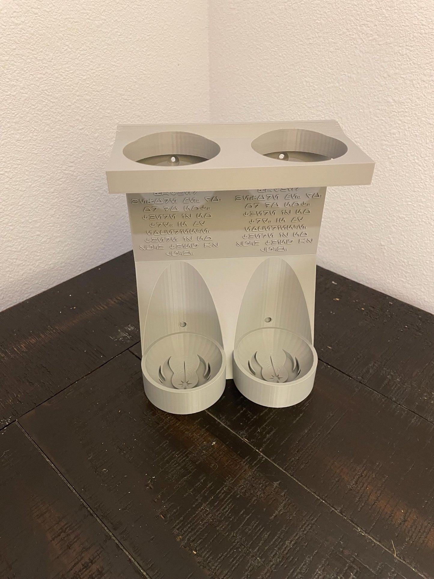 Savis Workshop Dual Lightsaber Mount shown here in the gray variant sitting on a table This vertical wall lightsaber mount is custom made to order every time. The aurebesh inscription is customizable as well as the logo in the hilt base.