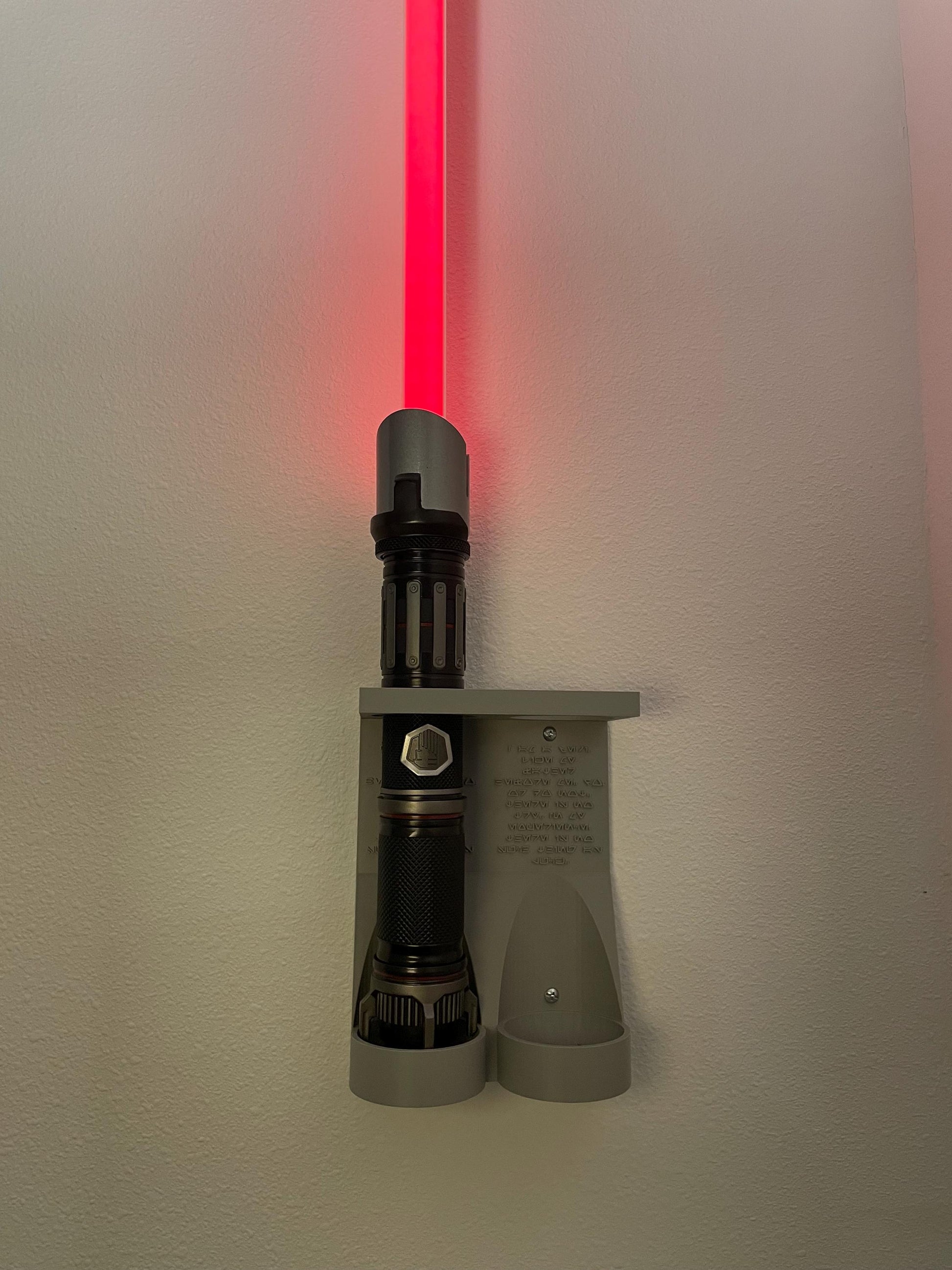Savi's Workshop Dual Lightsaber Mount by RobertsDesignandTech as shown in our Gray color variant is mounted on the wall display a power and control hand built lightsaber. Hardware for mounting to the wall is included in your purchase.