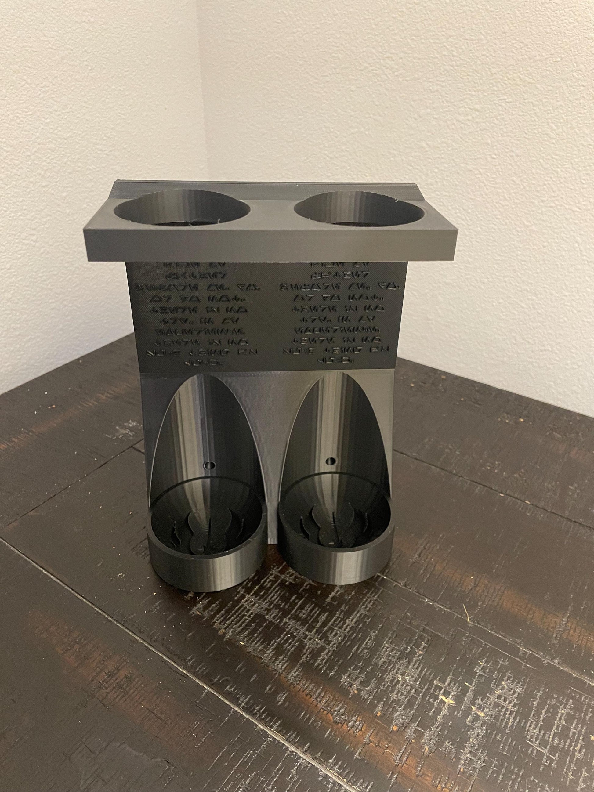 Savis Workshop Dual Lightsaber Mount shown here in the black variant sitting on a table This vertical wall lightsaber mount is custom made to order every time. The aurebesh inscription is customizable as well as the logo in the hilt base.